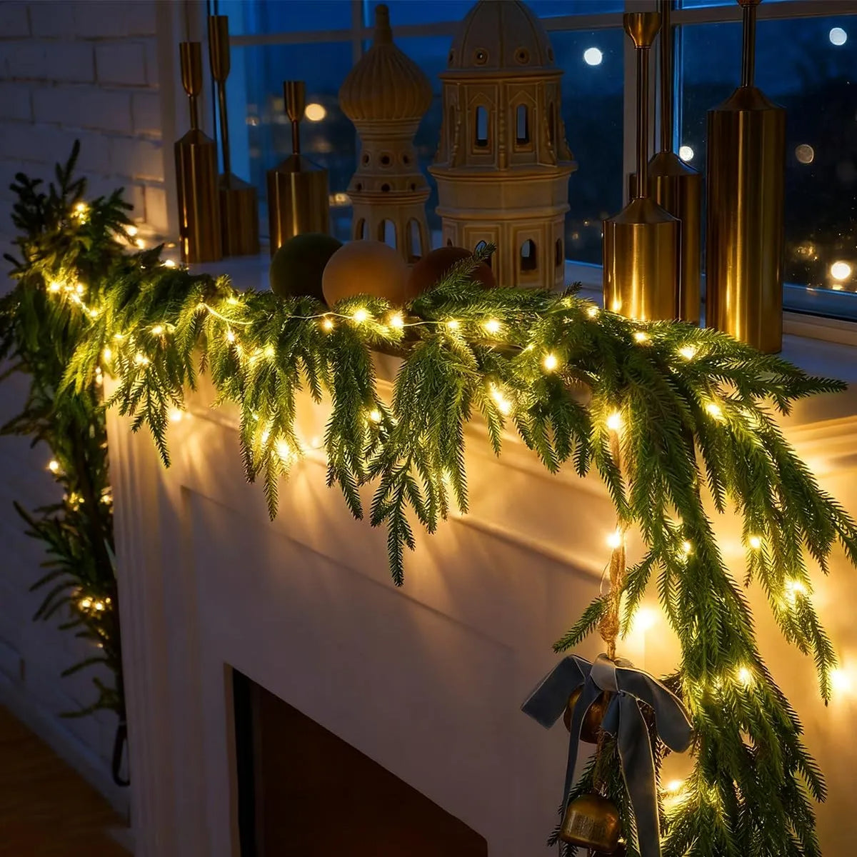 Warm white lights glowing through Norfolk-style pine garland on a mantel
