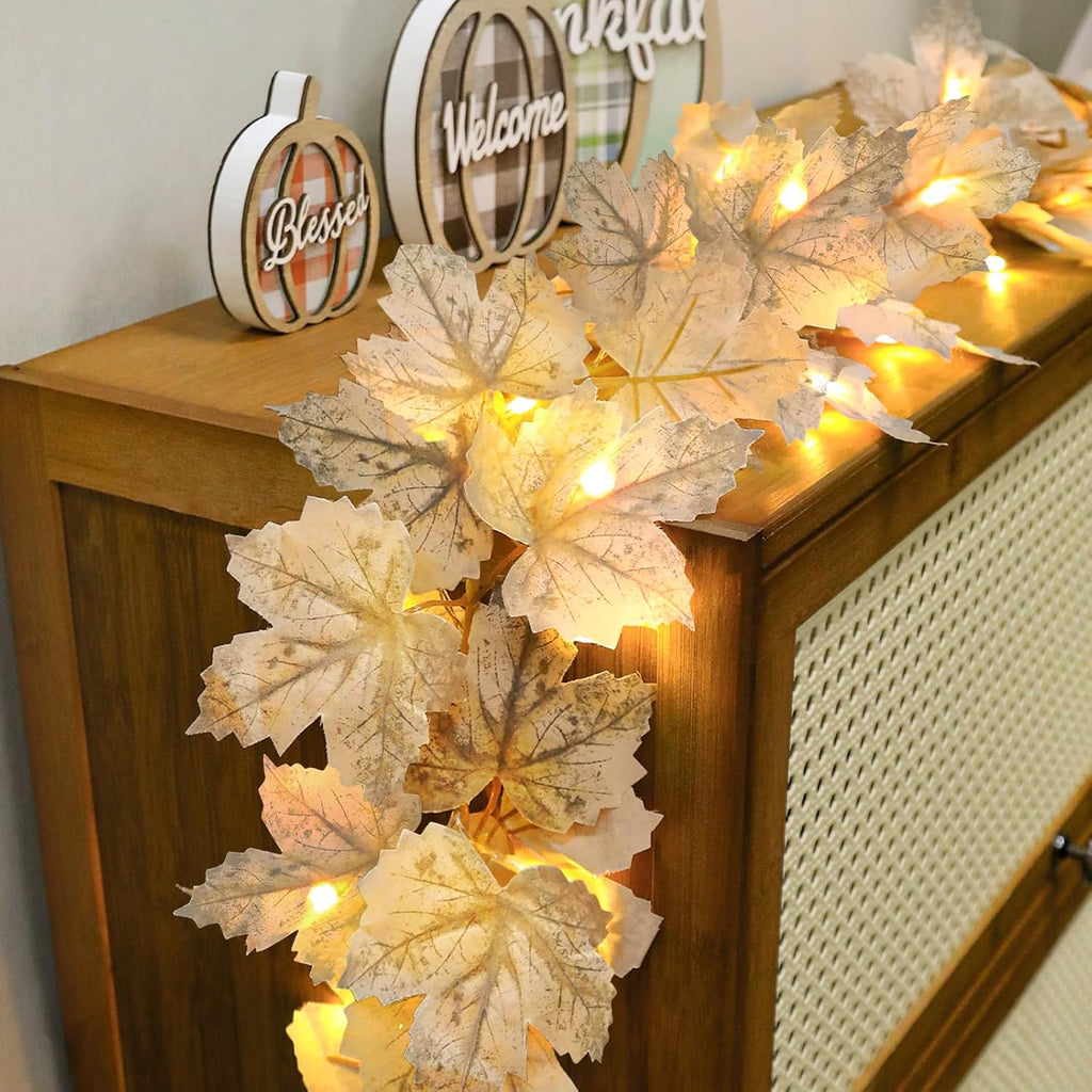 Warm-white maple leaf garland draped over a wooden cabinet